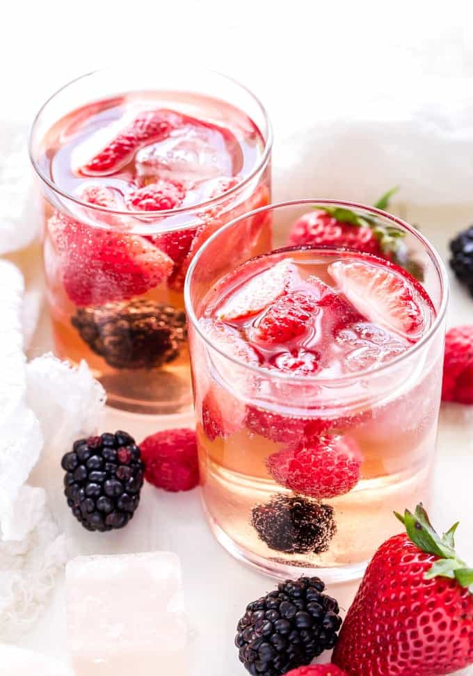deux verres transparents remplis de sangria rosée et de fraises et mûres fraîches