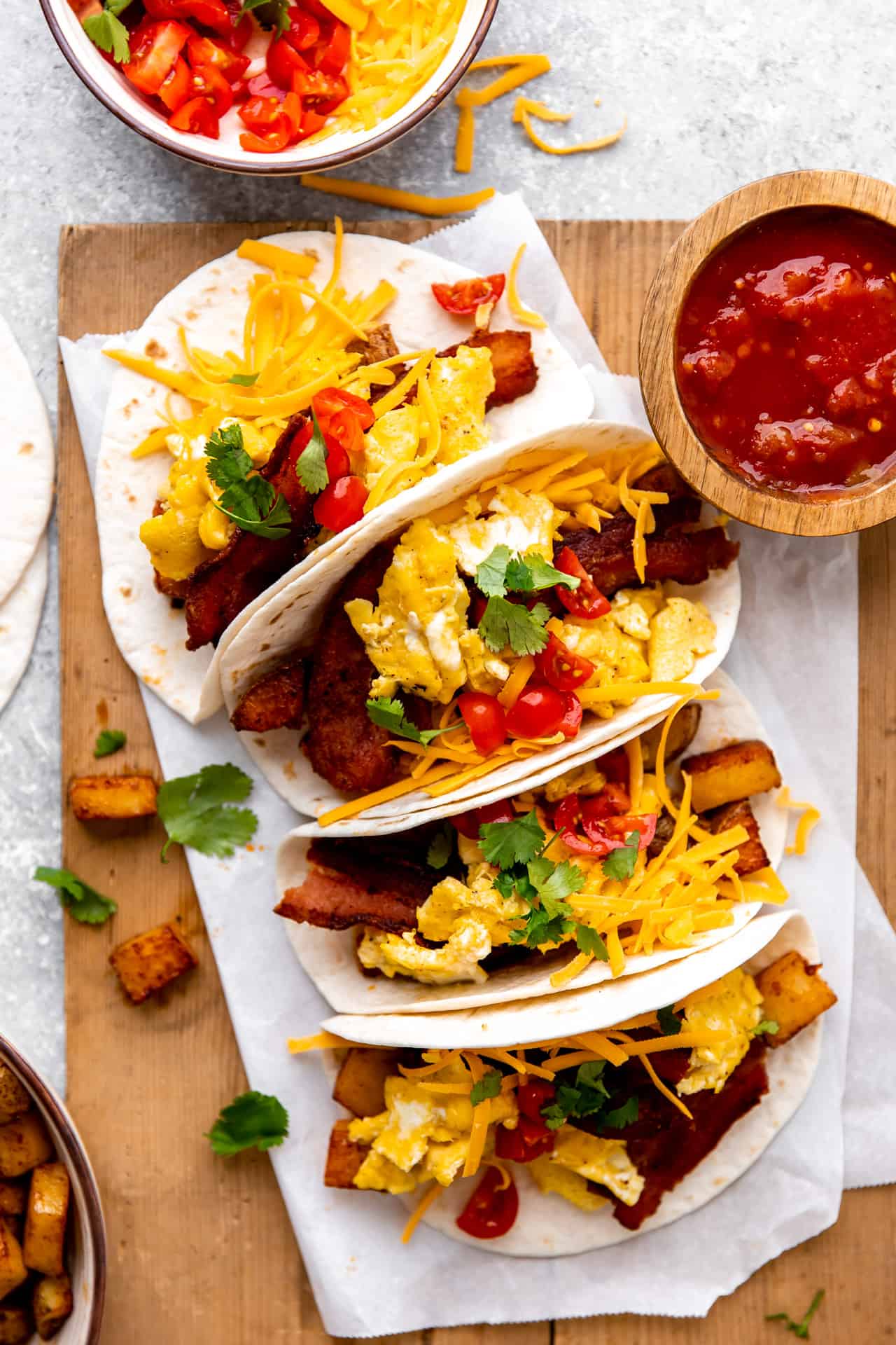 Plateau de tacos de petit-déjeuner chargés d'œufs, de bacon et de pommes de terre, servis avec de la salsa.