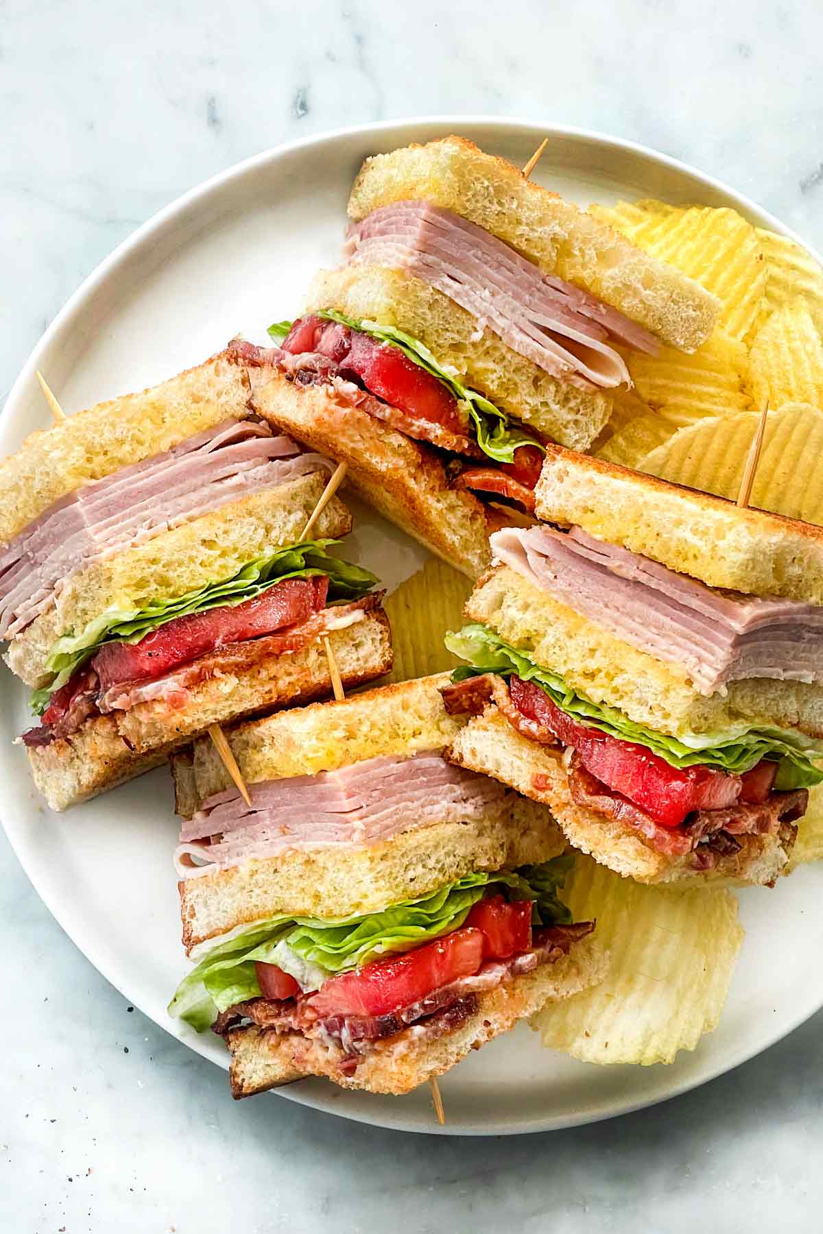 Club Sandwich avec cure-dents sur assiette avec chips foodiecrush.com