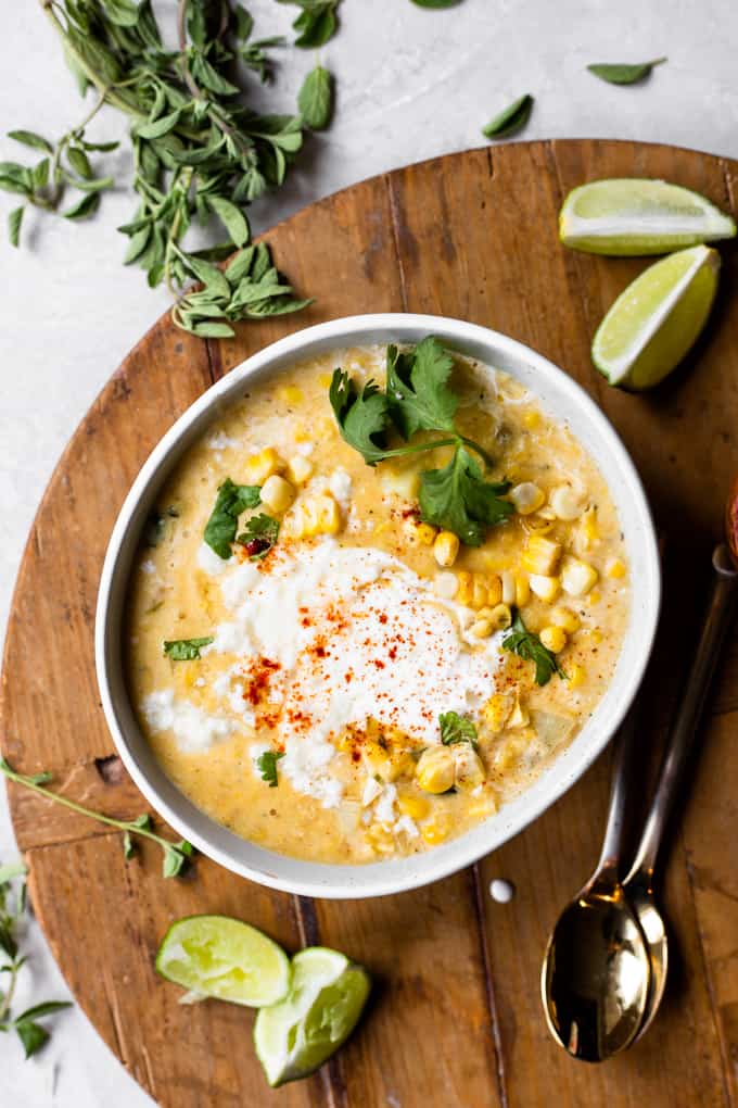 Bol de chaudrée de maïs mexicain servie avec un tourbillon de crème et de queso fresco émietté, quartiers de citron vert sur le côté.