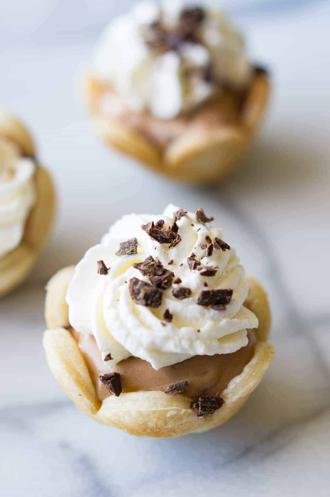 Mini-tartes françaises à la soie. Plus faciles à réaliser que vous ne le pensez, elles sont délicieusement savoureuses ! Du chocolat soyeux et crémeux, garni de crème fouettée maison. Le tout dans des mini-tartes de la taille d'une bouchée !