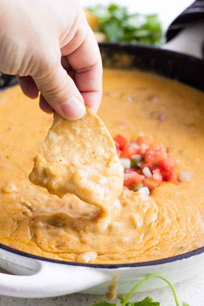 Une chips trempée dans du queso maison.