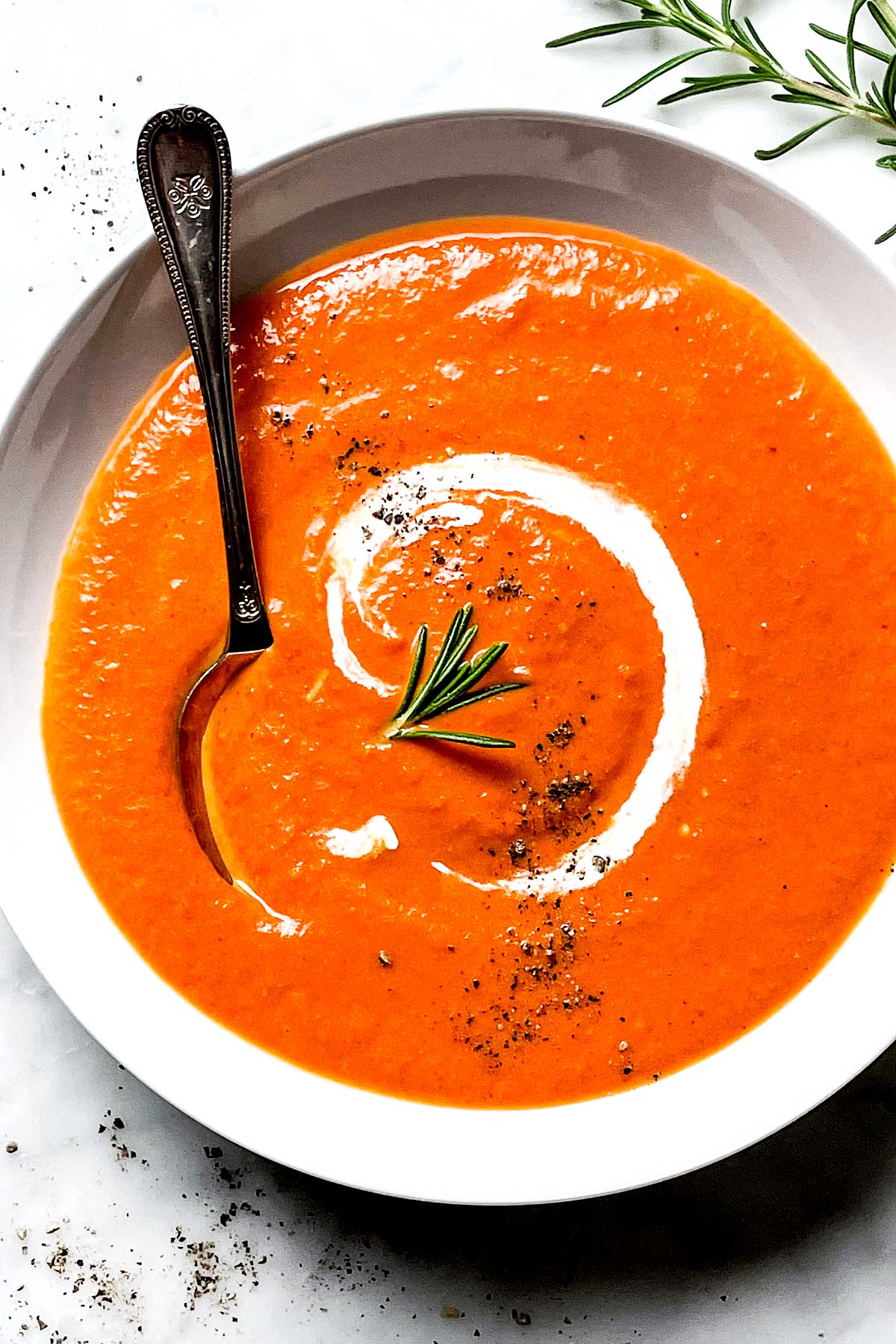 Soupe aux tomates et poivrons rouges grillés dans un bol avec une cuillère foodiecrush.com