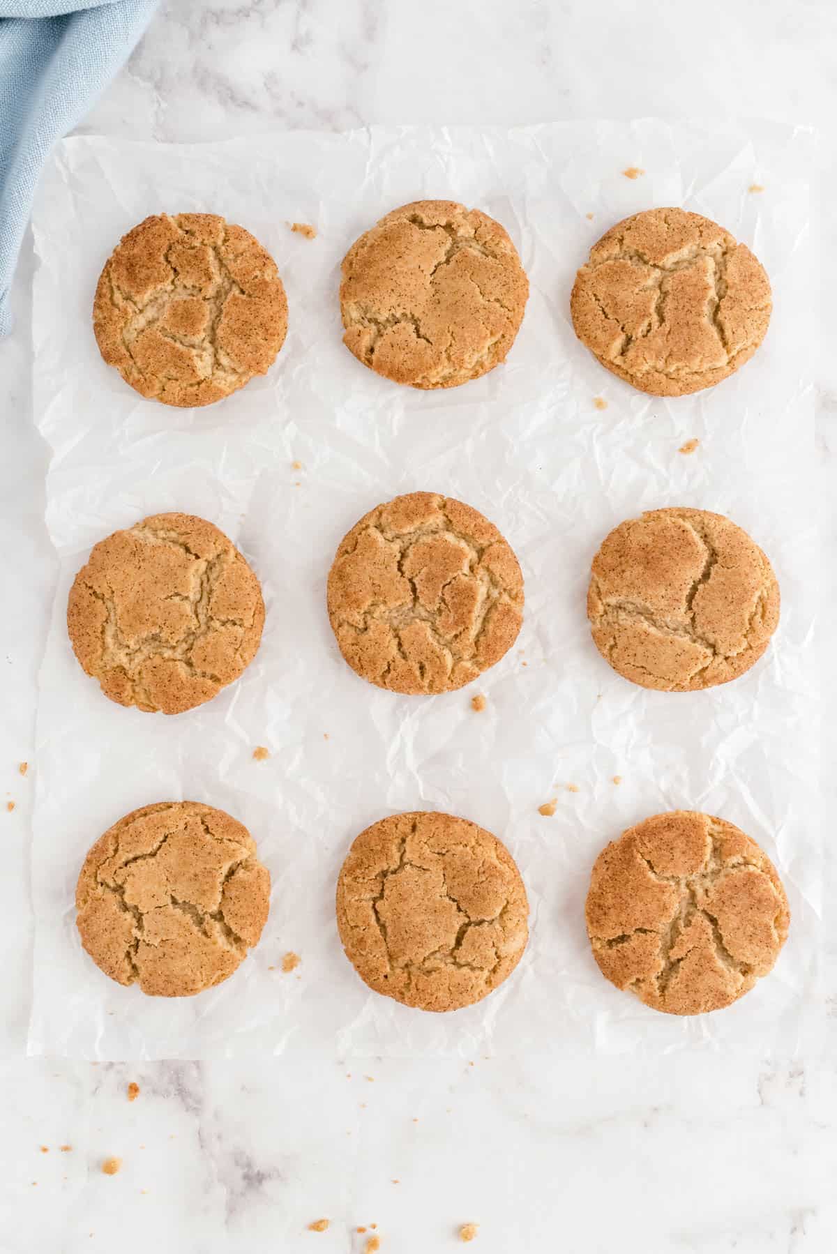 neuf snickerdoodles au beurre brun posés sur une feuille de papier sulfurisé blanc