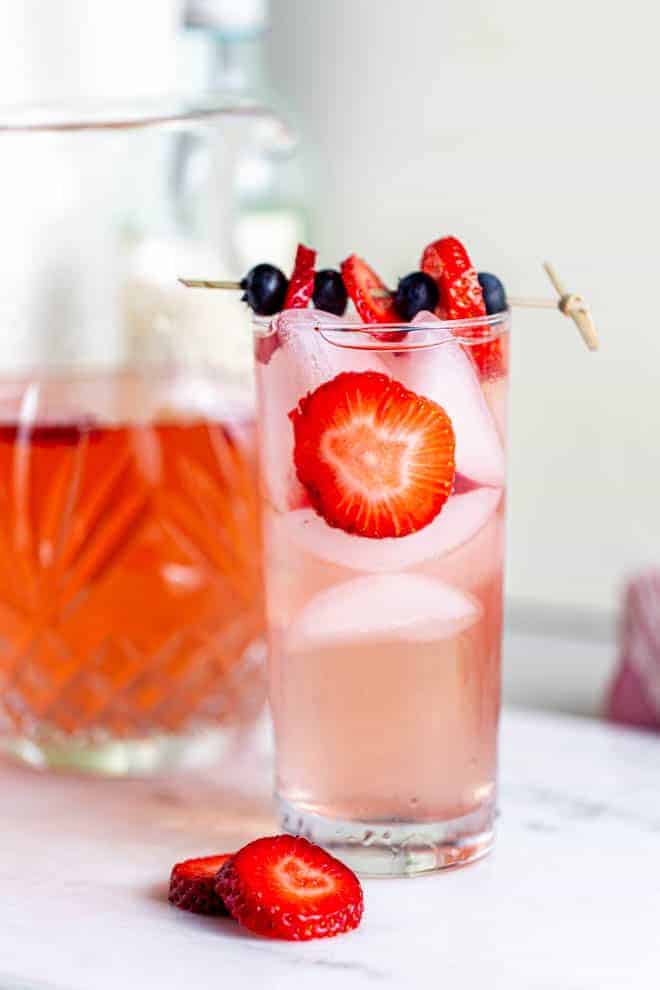 Un grand verre de sangria aux fraises avec des tranches de fraises fraîches.