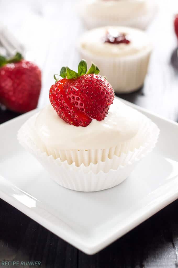 un cupcake aux anges fourré à la fraise posé sur une assiette carrée blanche