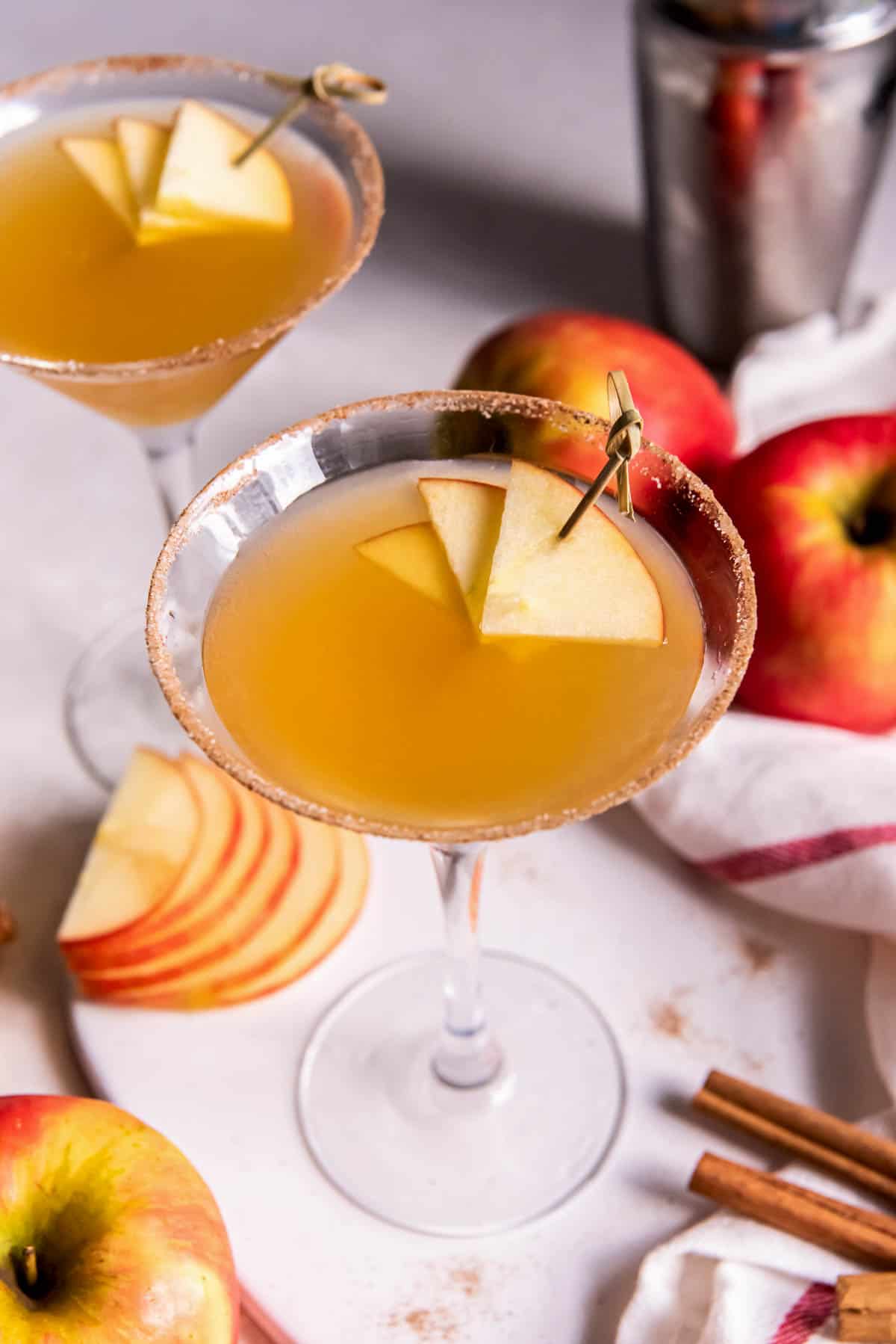 Deux martinis au cidre de pomme sur un comptoir avec une pomme tranchée à côté.