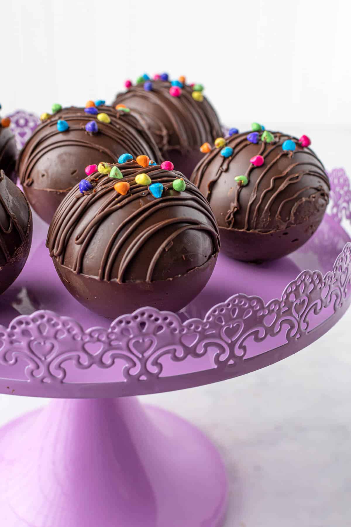 boules de chocolat chaud remplies de cacao chaud sur un support à gâteau violet