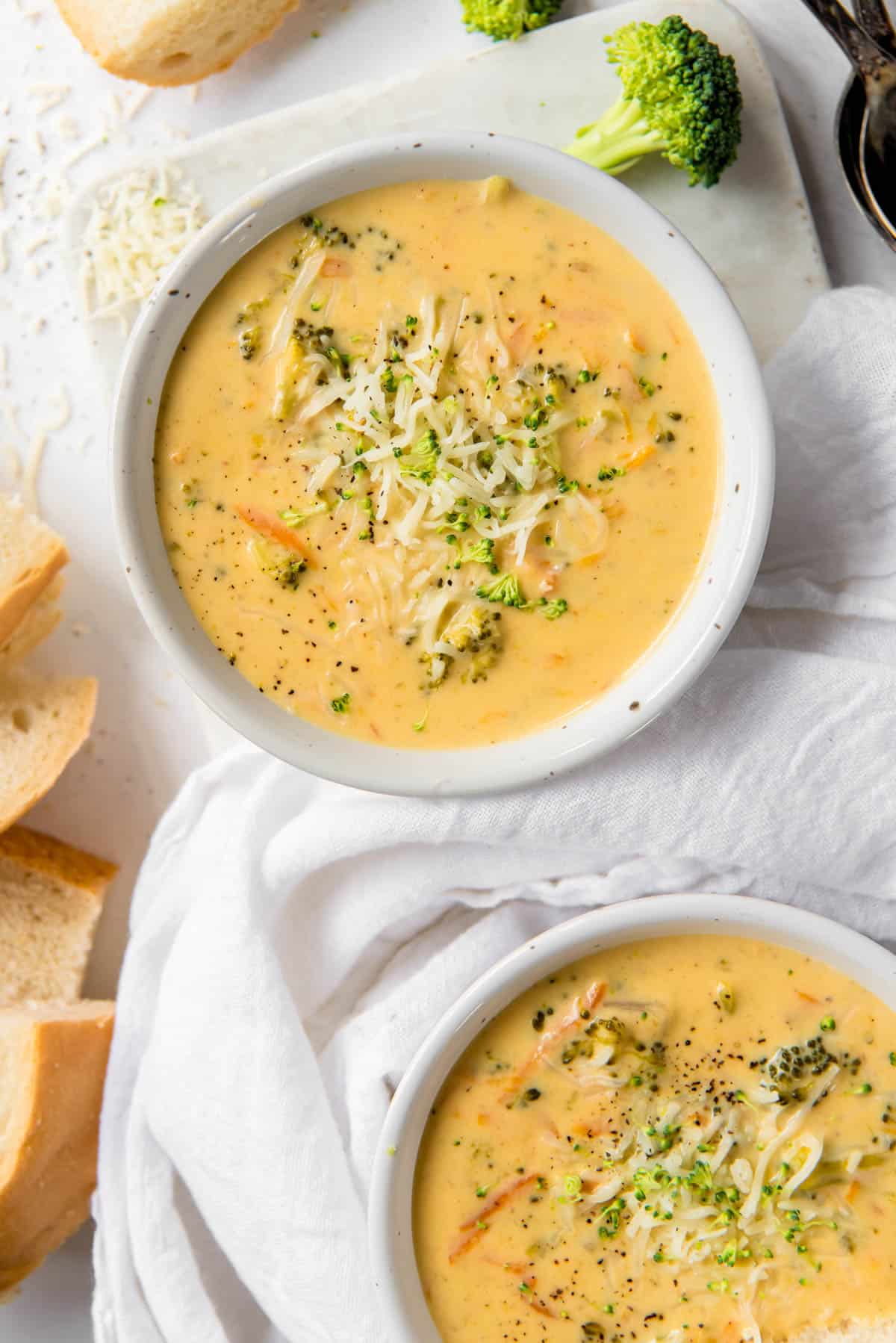 deux bols remplis de soupe au brocoli et au cheddar avec une pincée de fromage sur le dessus