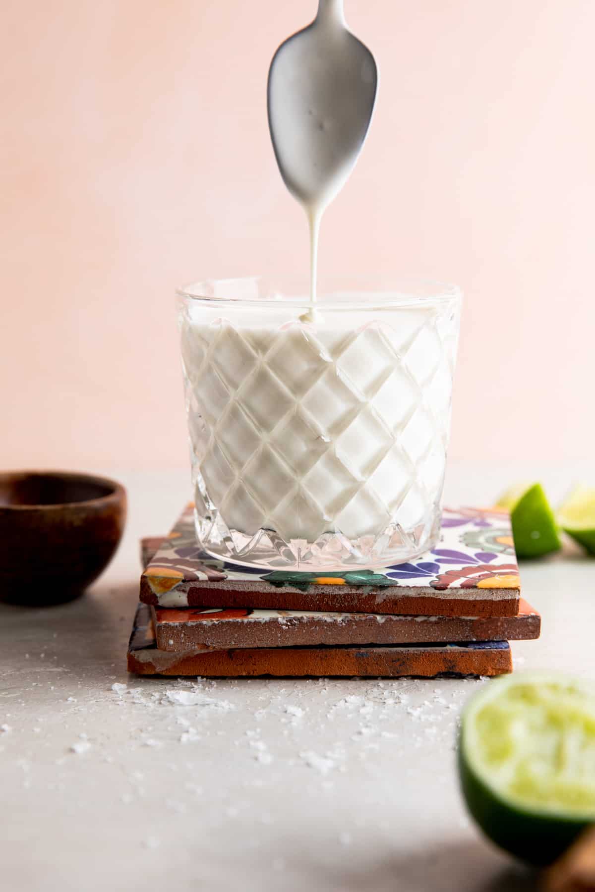 Coupe remplie de crème mexicaine maison avec une cuillère au-dessus pour arroser la crème.