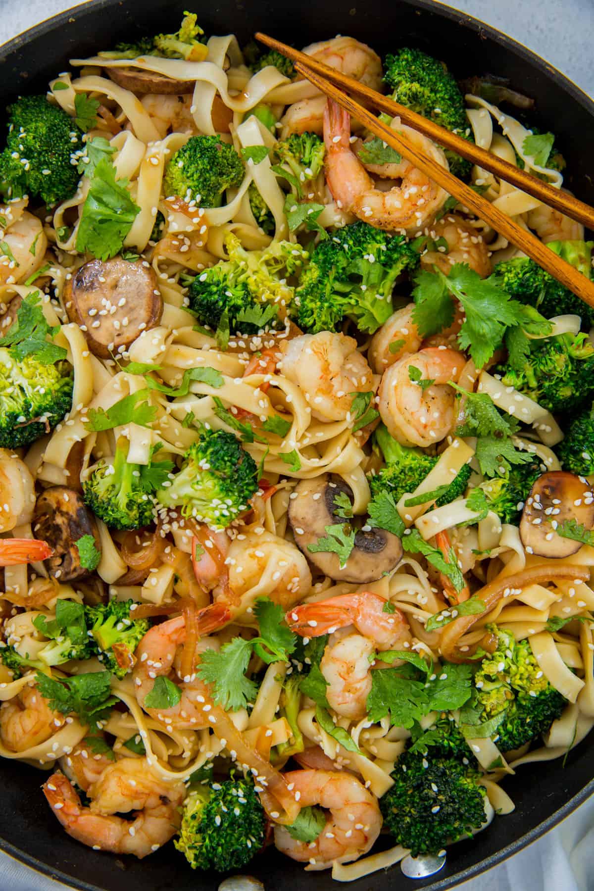 Nouilles Lo Mein faciles aux crevettes dans une poêle avec le brocoli prêt à servir.