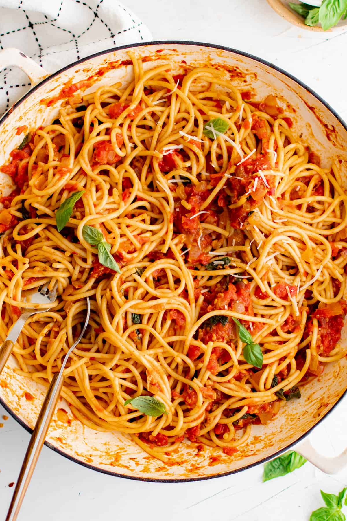 Une poêle remplie de spaghetti arrabbiata cuits et garnis de basilic haché.