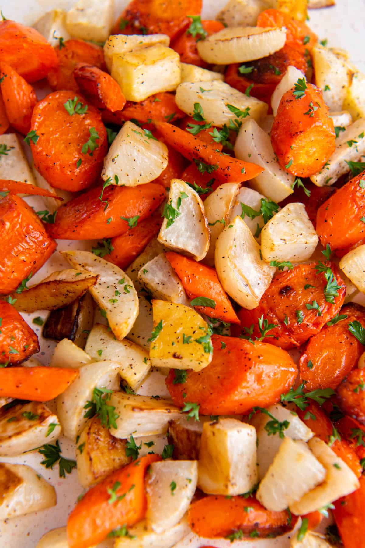 navets et carottes rôtis, empilés sur une plaque avec du persil haché